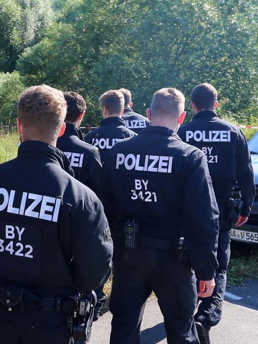 Polizisten durchsuchen am 19.07.2016 neben einem Weg bei Würzburg (Bayern) das Gelände nach Spuren. Am Montagabend war ein 17 Jahre alter Afghane mit einer Axt und einem Messer auf Fahrgäste in einem Regionalzug bei Würzburg-Heidingsfeld losgegangen.