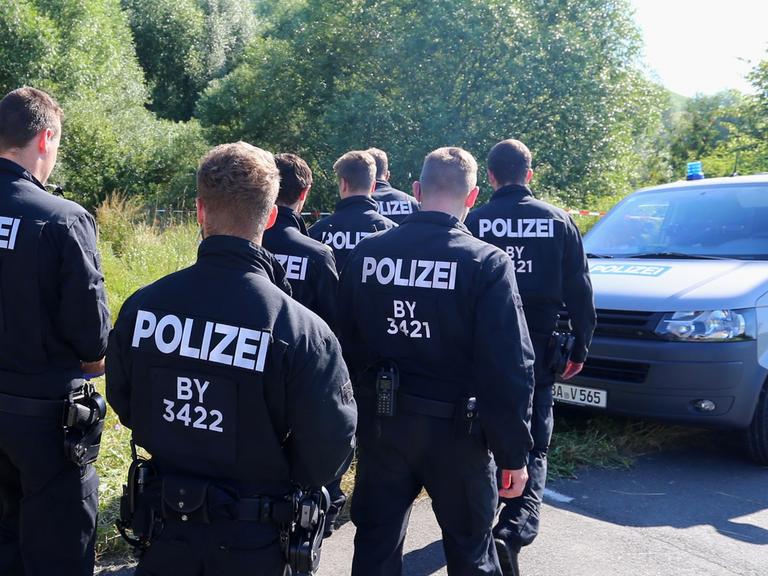 Polizisten durchsuchen am 19.07.2016 neben einem Weg bei Würzburg (Bayern) das Gelände nach Spuren. Am Montagabend war ein 17 Jahre alter Afghane mit einer Axt und einem Messer auf Fahrgäste in einem Regionalzug bei Würzburg-Heidingsfeld losgegangen.