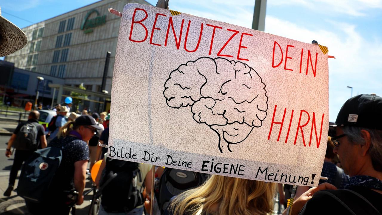 Demonstrierende ziehen durch Berlin und halten ein Schild hoch, auf das ein menschliches Gehirn gezeichnet ist und auf dem zu lesen ist: "Benutze dein Hirn". Demonstrierende ziehen durch Berlin und halten ein Schild hoch, auf das ein menschliches Gehirn gezeichnet ist und auf dem zu lesen ist: "Benutze dein Hirn".
