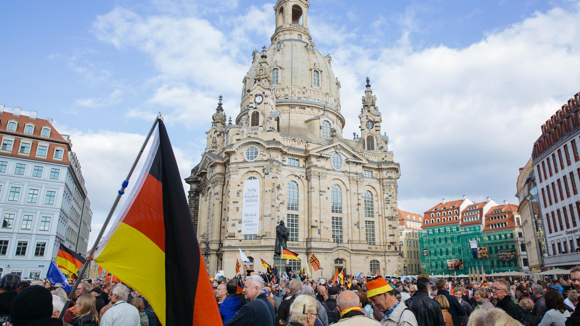 Teilnehmer einer Pegida-Demonstration stehen auf dem Neumarkt in Dresden, im Hintergrund die Frauenkirche.