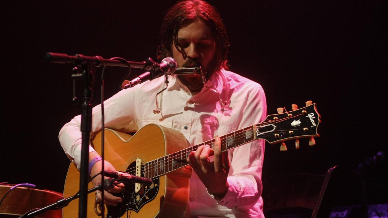 Ein Mann spielt Gitarre auf einer Bühne.