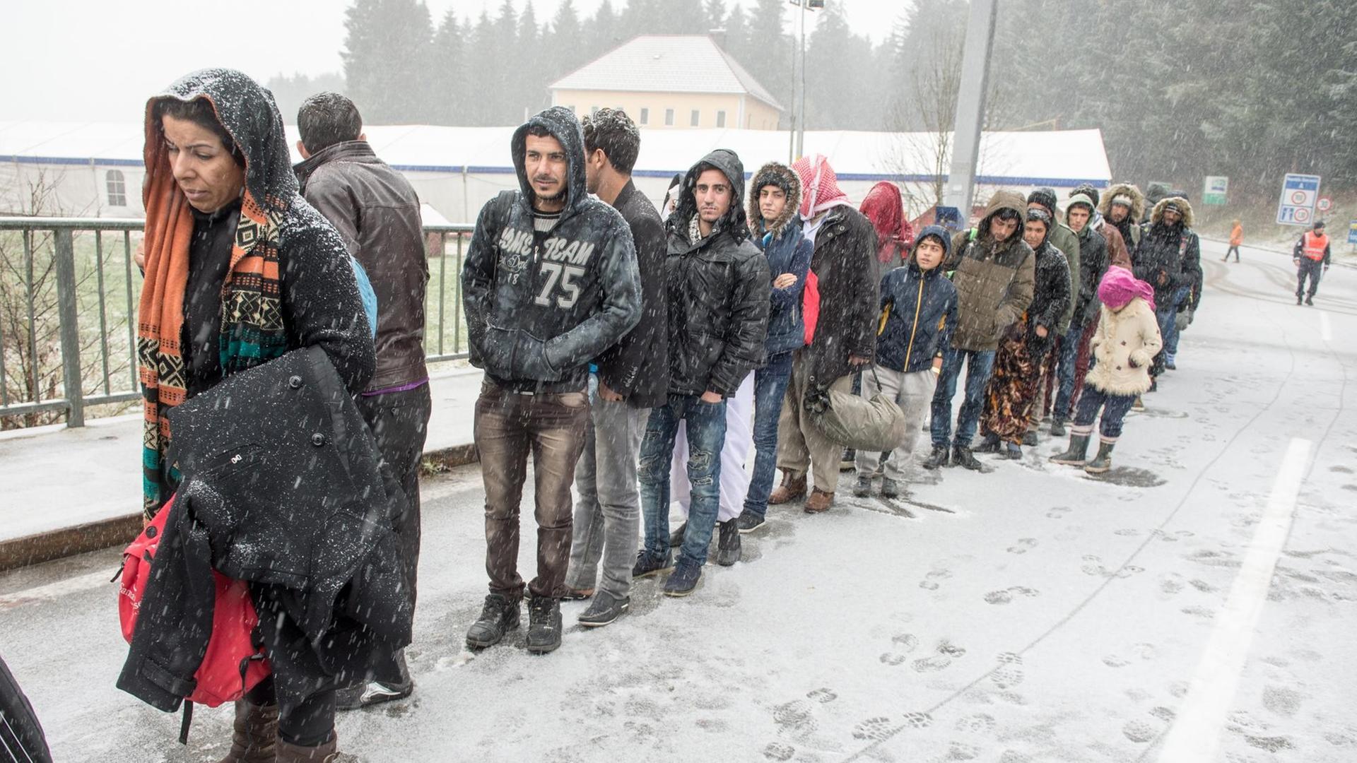 Flüchtlinge warten am 21.11.2015 an der deutsch-österreichischen Grenze nahe Wegscheid (Bayern) während eines Schneeschauers auf ihre Einreise nach Deutschland.