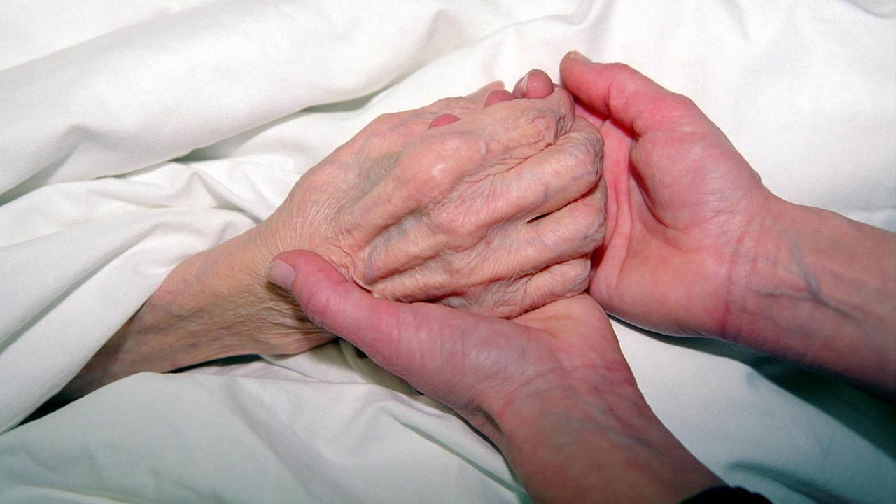 Einer sterbenden Frau wird die Hand gehalten Einer sterbenden Frau wird die Hand gehalten