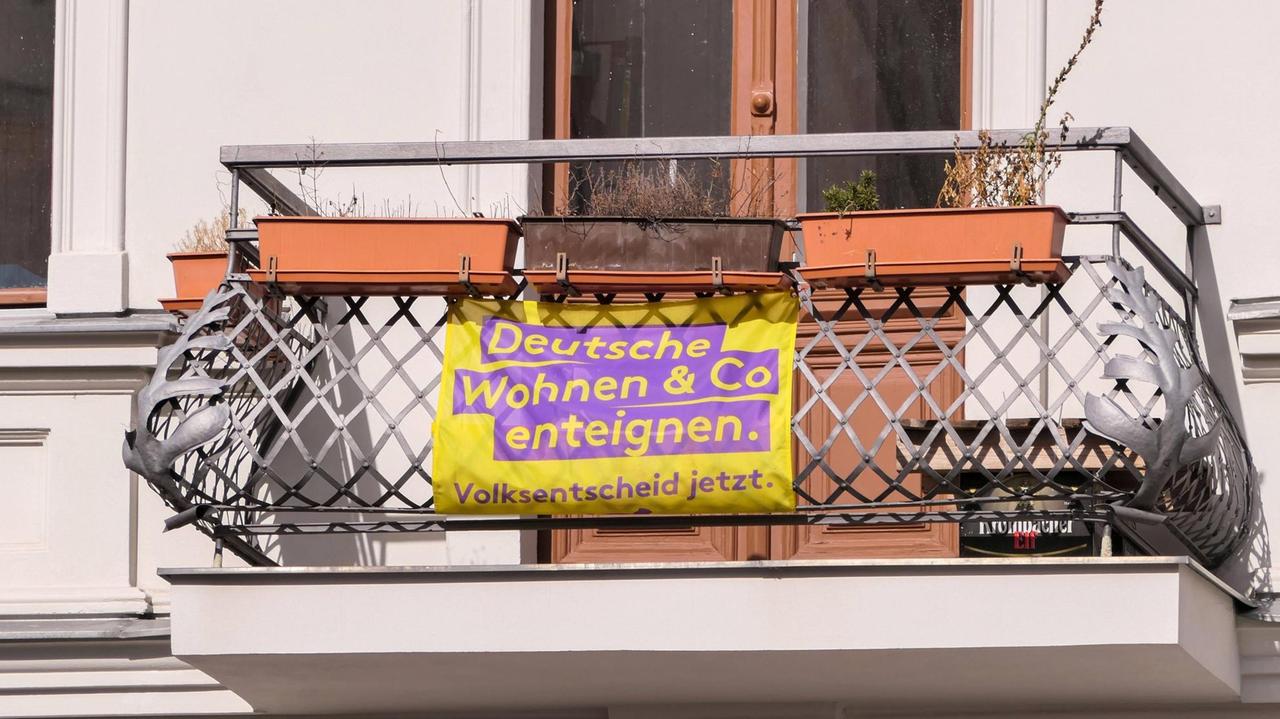 An einem Balkon eines Altbaus hängt ein Transparent, auf dem steht: Deutsche Wohnen und Co enteignen An einem Balkon eines Altbaus hängt ein Transparent, auf dem steht: Deutsche Wohnen und Co enteignen