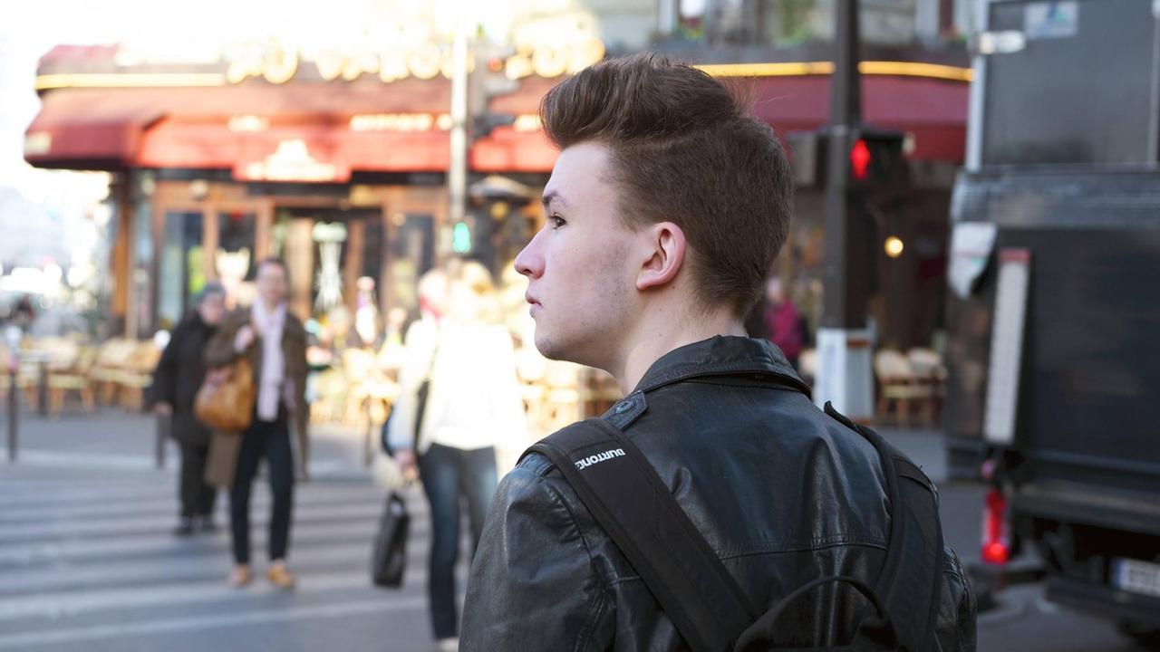 Ein Schüler geht über eine belebte Straße in Paris Ein Schüler geht über eine belebte Straße in Paris