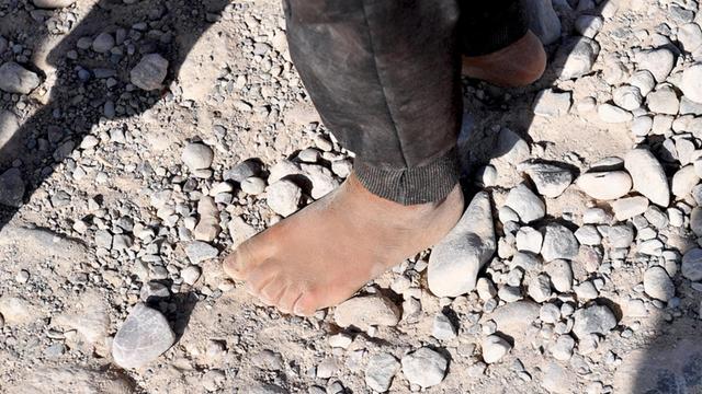 Ein Kind läuft im Flüchtlingscamp Mamilian in der Region Dohuk (Irak) barfuß über einen steinigen Weg.