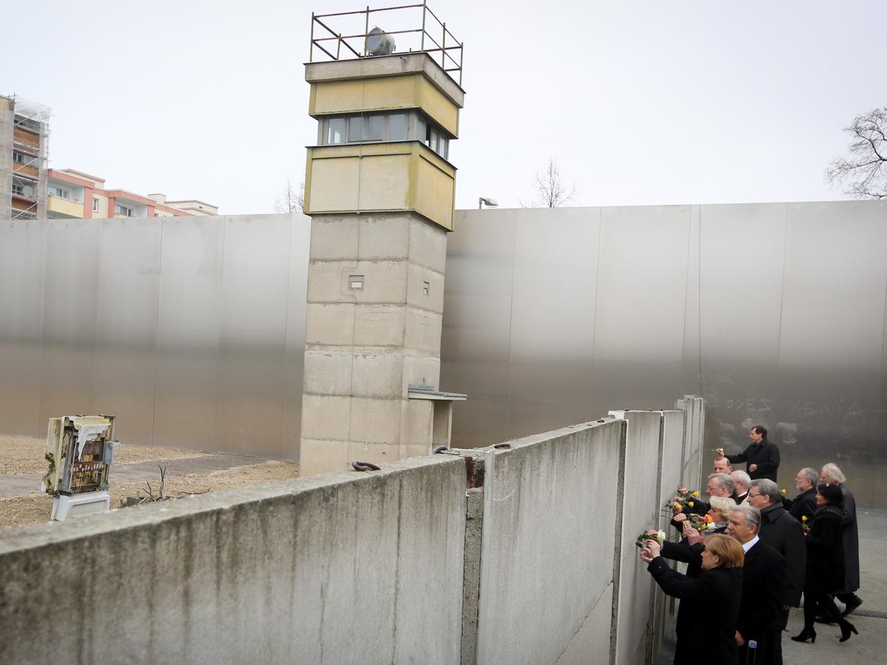 Bundeskanzlerin Angela Merkel, Klaus Wowereit und andere Politiker stecken zum Auftakt der Gedenkveranstaltung zum 25. Jahrestag des Mauerfalls an der Gedenkstätte Bernauer Straße Rosen in einen Mauerspalt, dahinter ragt ein ehemaliger Wachturm auf Bundeskanzlerin Angela Merkel, Klaus Wowereit und andere Politiker stecken zum Auftakt der Gedenkveranstaltung zum 25. Jahrestag des Mauerfalls an der Gedenkstätte Bernauer Straße Rosen in einen Mauerspalt, dahinter ragt ein ehemaliger Wachturm auf