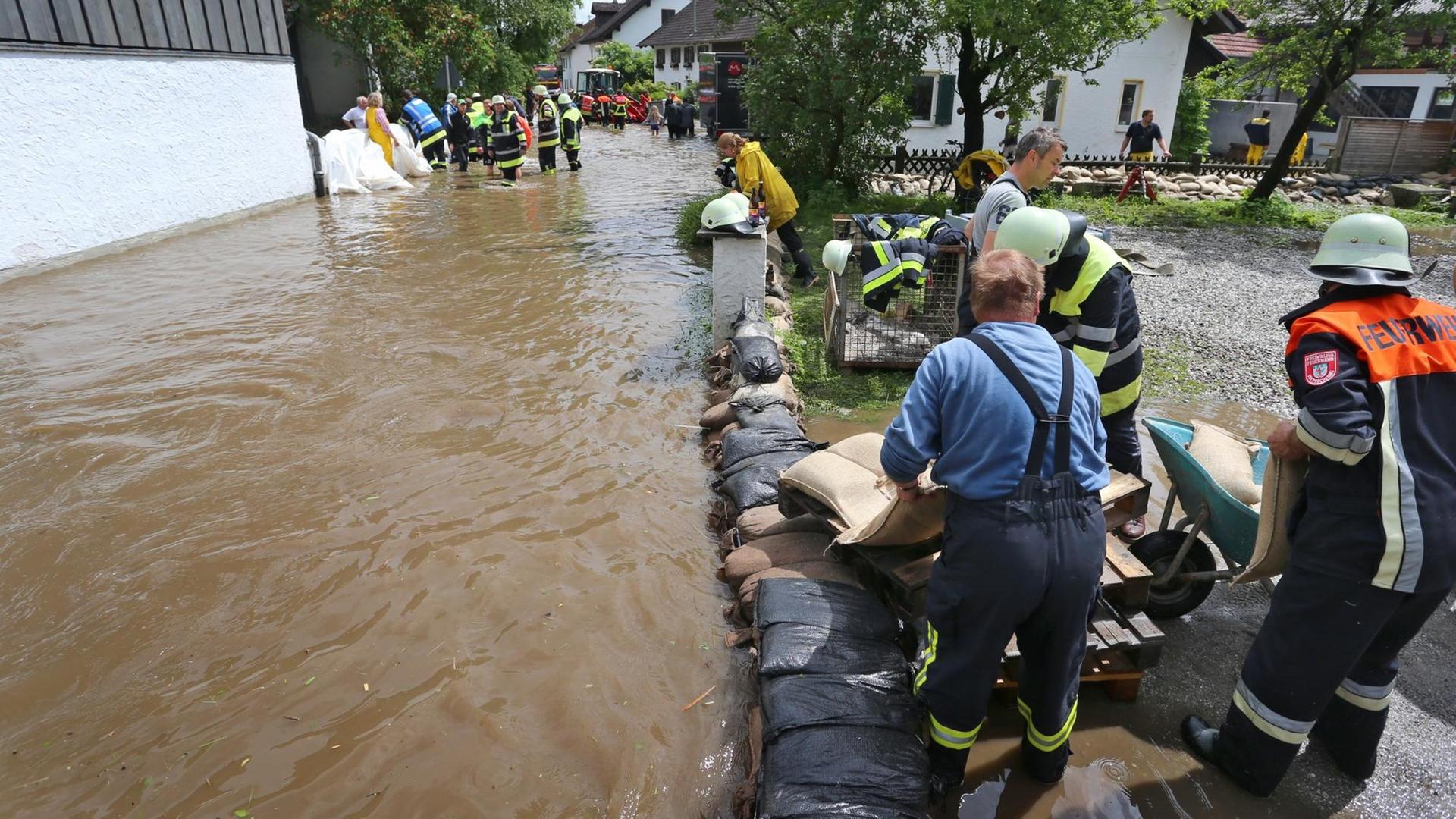 Helfer arbeiten in dem vom Tiefenbach überfluteten Polling (Bayern). Unwetter mit starkem Regen und zum Teil kräftigen Gewittern haben vielen Menschen in Bayern erneut schwer zu schaffen gemacht. Helfer arbeiten in dem vom Tiefenbach überfluteten Polling (Bayern). Unwetter mit starkem Regen und zum Teil kräftigen Gewittern haben vielen Menschen in Bayern erneut schwer zu schaffen gemacht.
