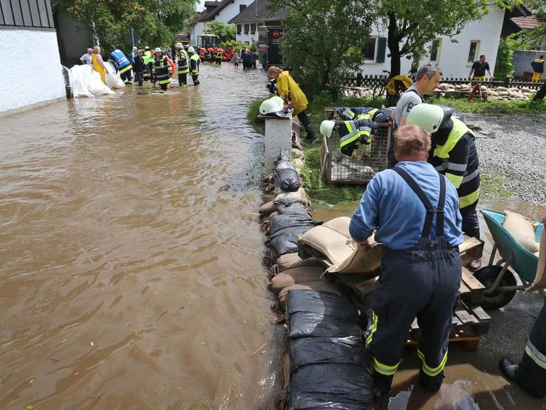 Helfer arbeiten in dem vom Tiefenbach überfluteten Polling (Bayern). Unwetter mit starkem Regen und zum Teil kräftigen Gewittern haben vielen Menschen in Bayern erneut schwer zu schaffen gemacht.