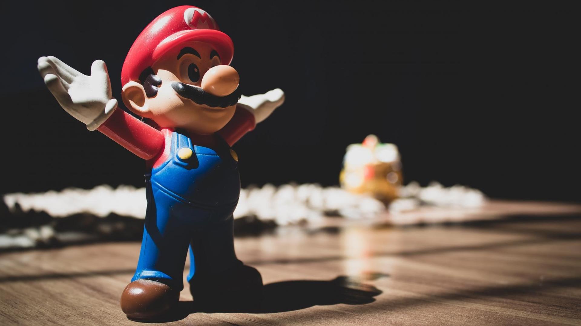 Eine Figur aus dem Spiel Super-Mario steht mit ausgebreiteten Armen auf einem Tisch