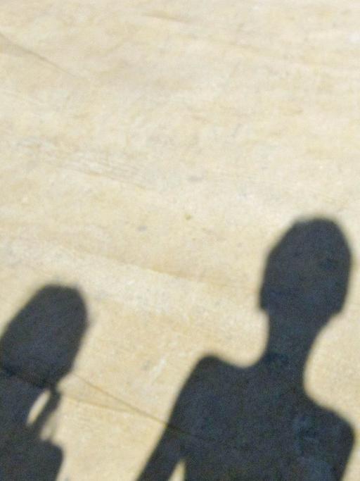 Der Schatten einer Familie, die sich an der Hand hält.