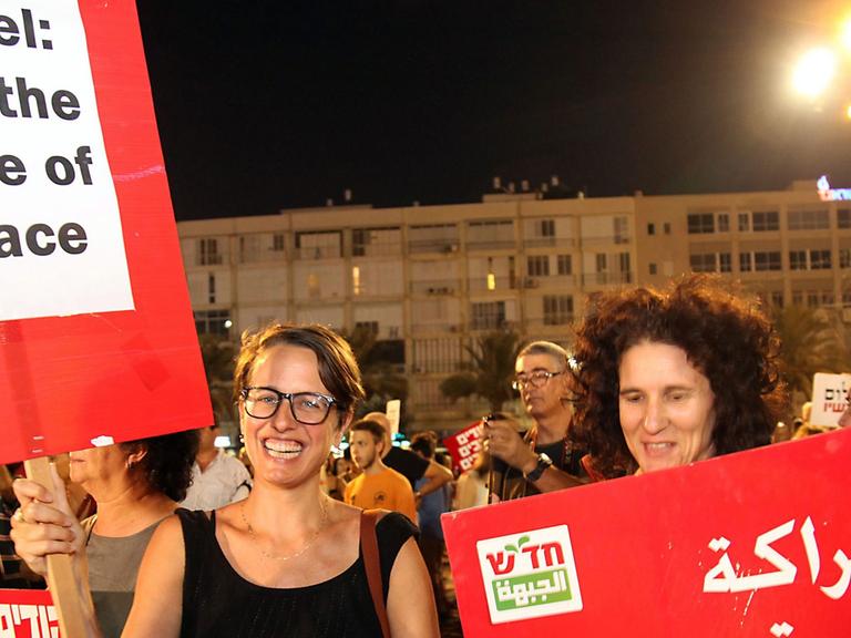 Israelische Demonstranten fordern halten Schilder mit der Aufschrift "Israel: Pay the price of peace" in Englisch und Arabisch auf dem Tel Aviver Rabin-Platz am 16. August 2014. Sie fordern Frieden zwischen Israelis und Palästinensern.
