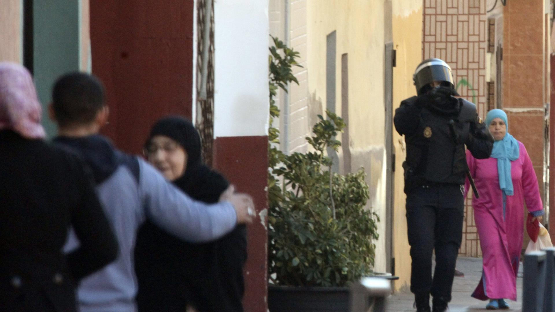 Ein Polizist läuft zwischen muslimischen Bewohnern nachdem die Polizei vier mutmaßliche Dschihadisten in El Principe, einem Randgebiet von Ceuta, am 24.01.2015 festgenommen hatte.