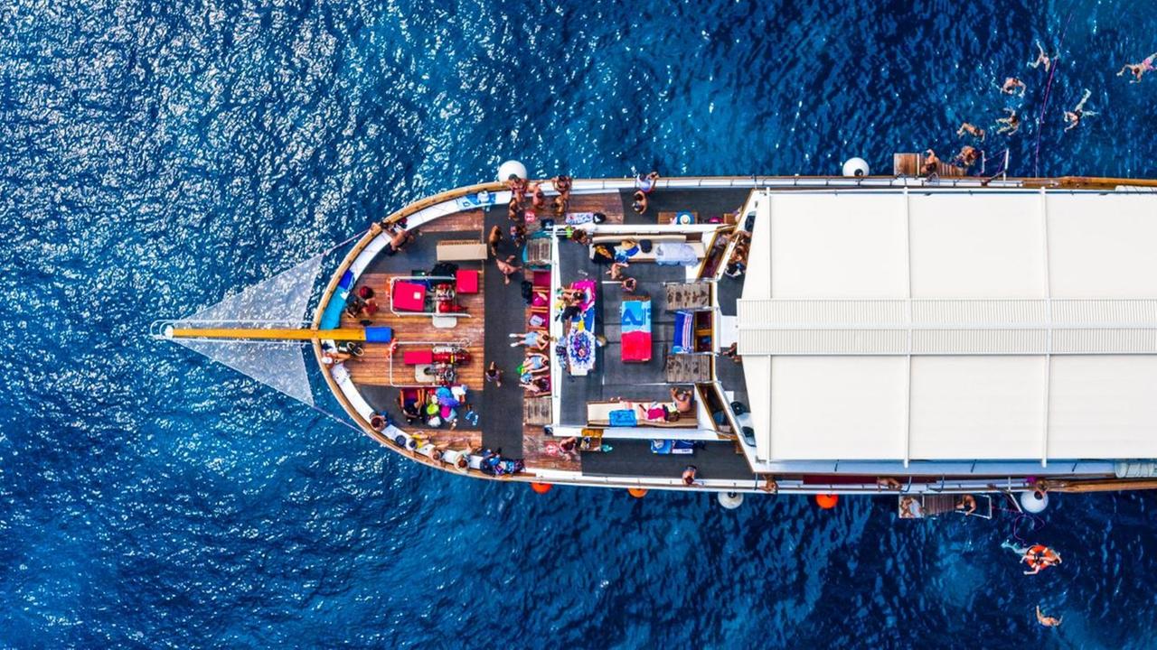 Luftaufnahme von einem Kreuzfahrtschiff im glasklaren blauen Meer Luftaufnahme von einem Kreuzfahrtschiff im glasklaren blauen Meer