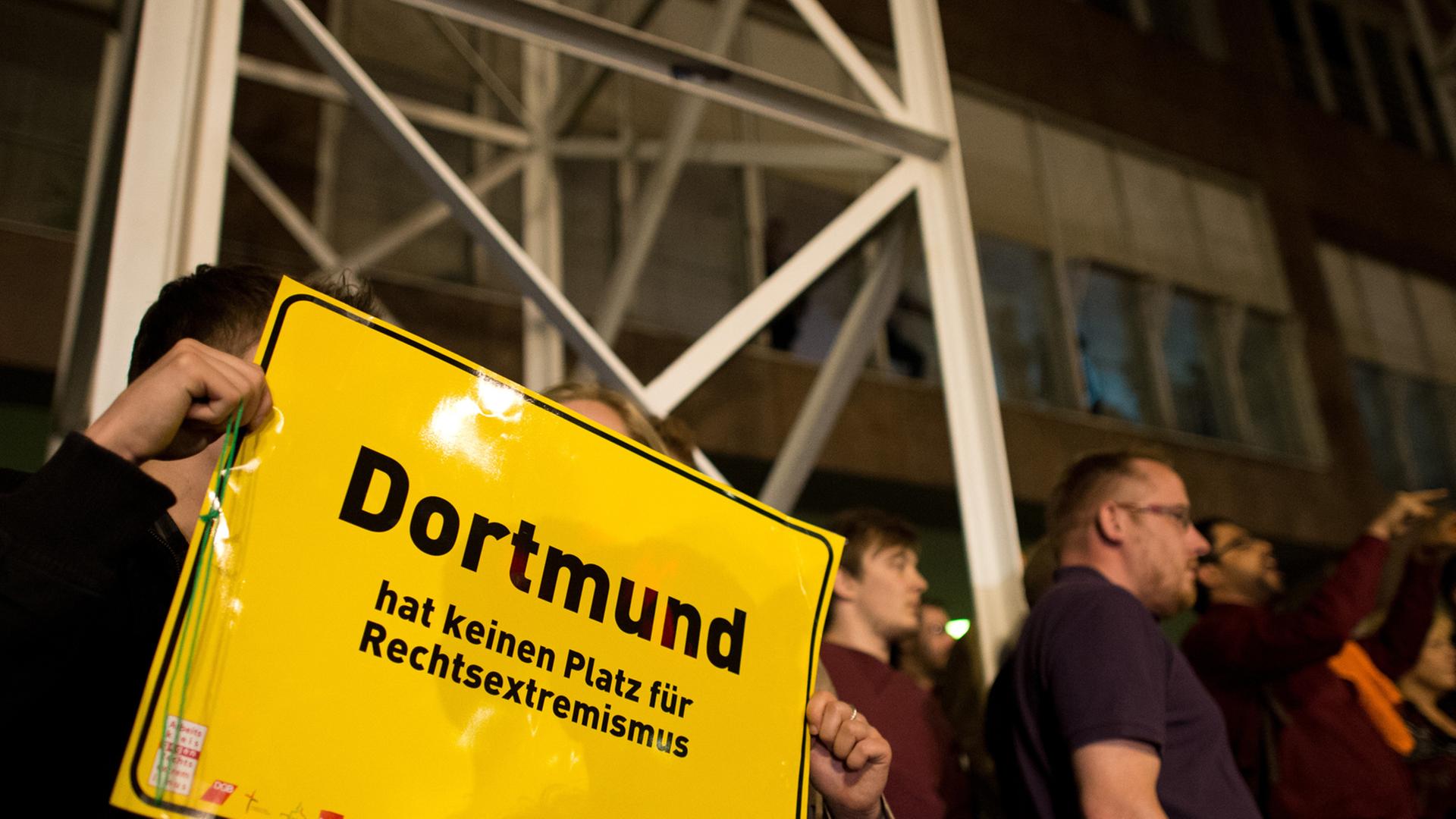 Ein Mann und eine Frau zeigen am 25.05.2014 vor dem Rathaus in Dortmund (Nordrhein-Westfalen) ein Schild mit der Aufschrift "Dortmund hat keinen Platz für Rechtsextremismus". Eine Gruppe von Männern aus dem rechten Umfeld hatten versucht, das Rathaus am Wahlabend zu stürmen, wurde daran aber von Bürgern gehindert.