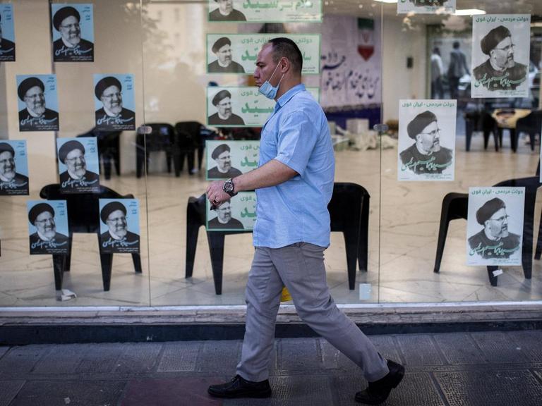 Passant in Teheran vor Wahlplakaten für die Präsidentschaftswahl 2021 im Iran