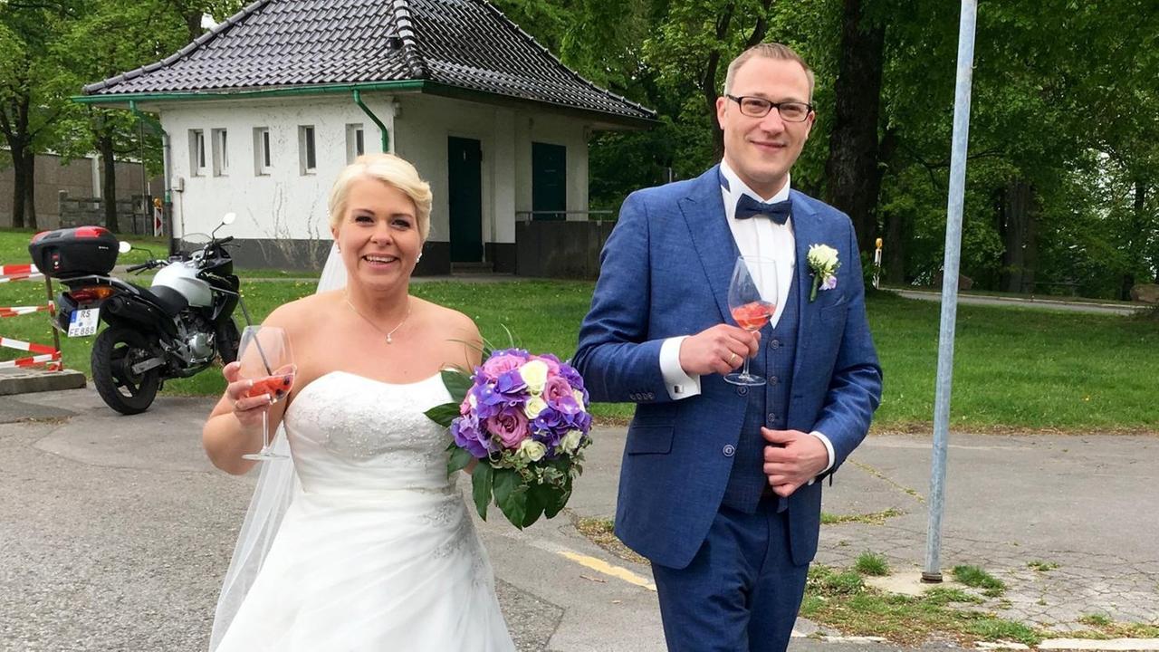 Das Hochzeitspaar geht mit einem Glas in der Hand über den Hof Das Hochzeitspaar geht mit einem Glas in der Hand über den Hof