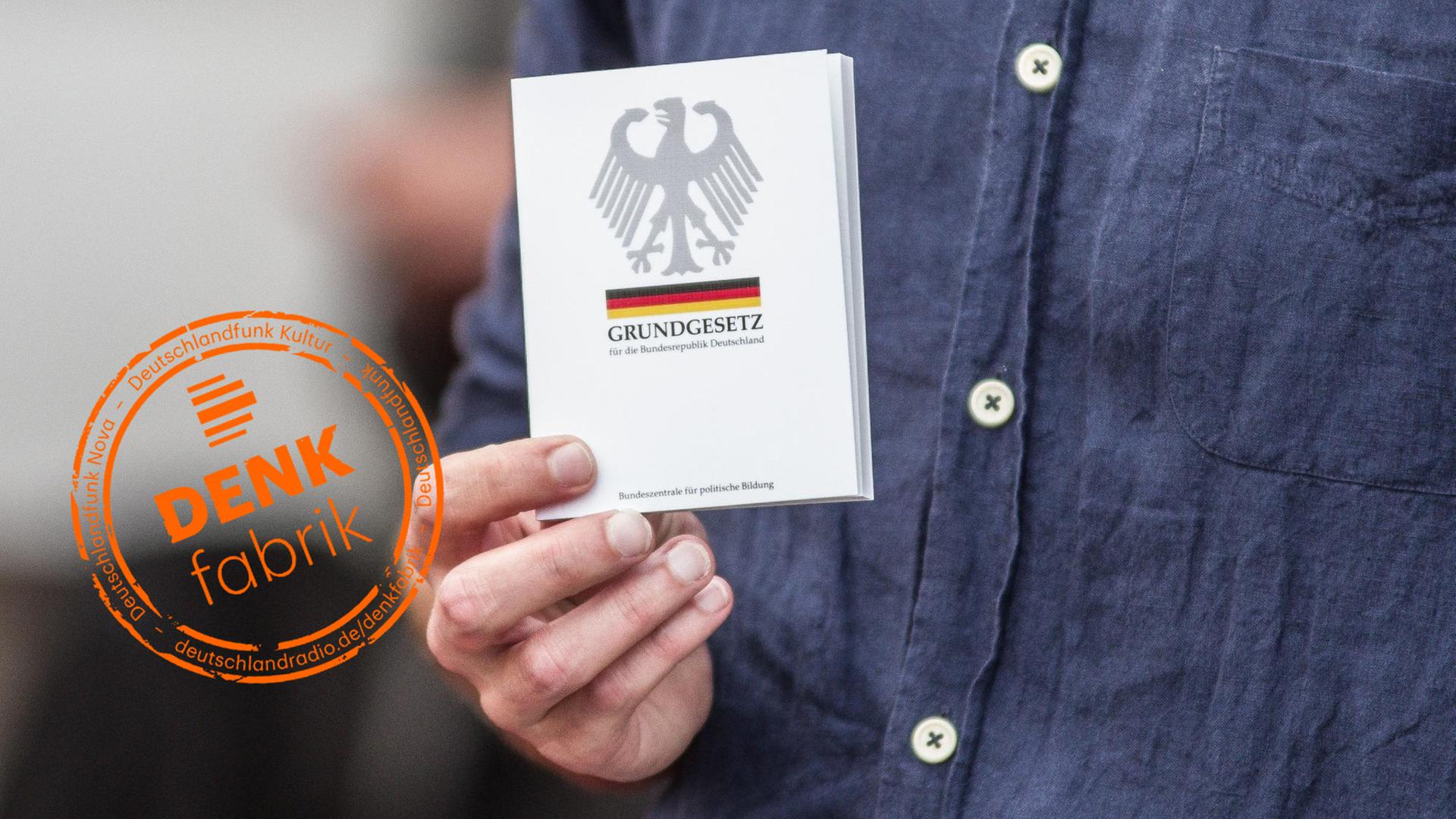 Ein Mann hält das deutsche Grundgesetz in seiner Hand