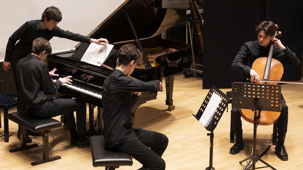 Ein Klaviertrio spielt auf der Bühne ein Konzert Ein Klaviertrio spielt auf der Bühne ein Konzert