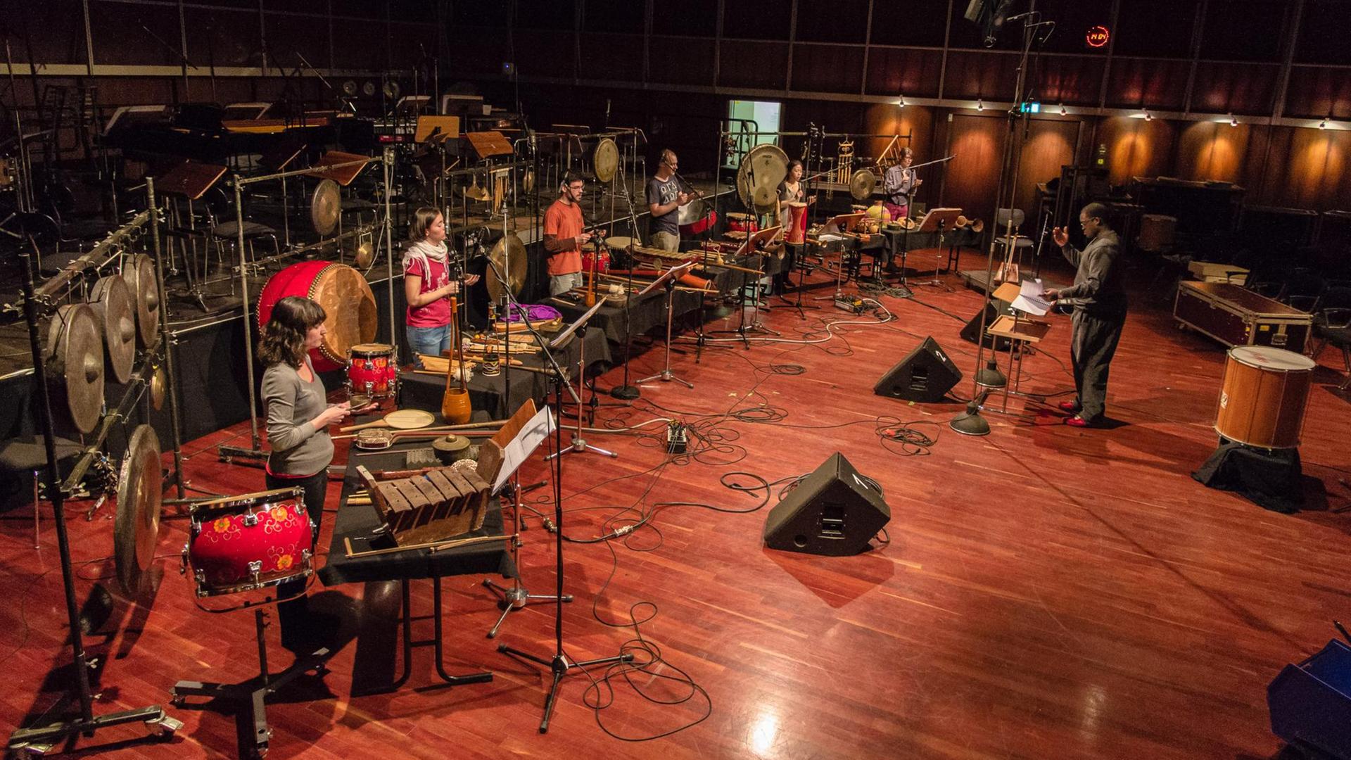 Sech Musikerinnen und Musiker stehen im Halbkeis hinter Schlagwerk-Instrumenten. Vor Ihnen in der Mitte steht der musikalische Leiter hinter einem Notenpult Sech Musikerinnen und Musiker stehen im Halbkeis hinter Schlagwerk-Instrumenten. Vor Ihnen in der Mitte steht der musikalische Leiter hinter einem Notenpult