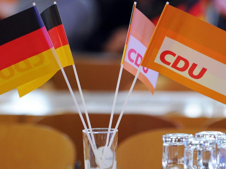 In einem Wasserglas stecken zwei kleine Deutschland- und zwei kleine CDU-Flaggen