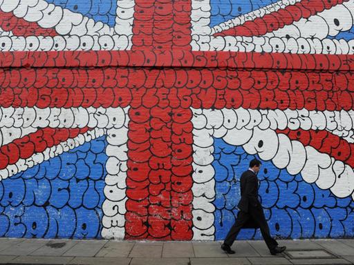 epa03105488 A man walks by a giant graffiti mural depicting the Union Jack in London, Britain, on 14 February 2012. Credit ratings agency Moody's has issued official notice to Britain and the Bank of England that their AAA credit ratings are at risk of a potential downgrade. EPA/FACUNDO ARRIZABALAGA |