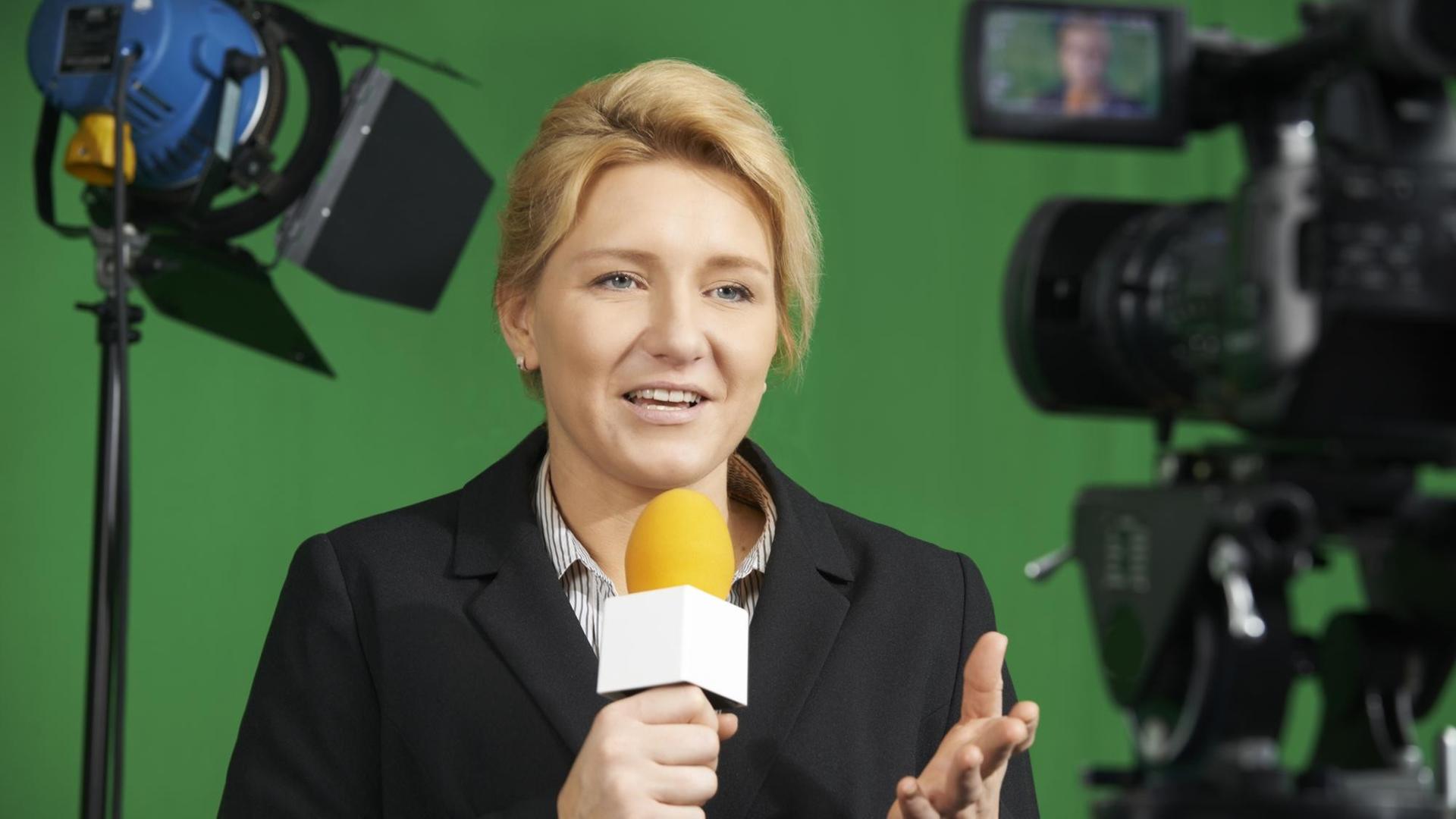 Moderatorin im Fernsehstudio durch die Anzeige einer Kamera gesehen (Symbolfoto). Moderatorin im Fernsehstudio durch die Anzeige einer Kamera gesehen (Symbolfoto).