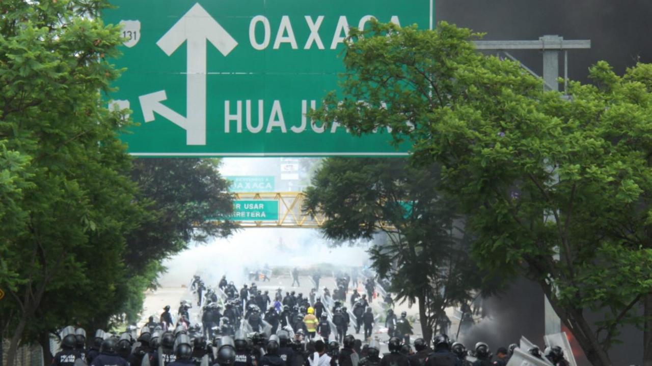 Die Polizei geht gegen Gegner der Bildungsreform in Oaxaca in Mexiko vor. Außerdem sieht man ein großes Verkehrshinweisschild nach Oaxaca. Die Polizei geht gegen Gegner der Bildungsreform in Oaxaca in Mexiko vor. Außerdem sieht man ein großes Verkehrshinweisschild nach Oaxaca.