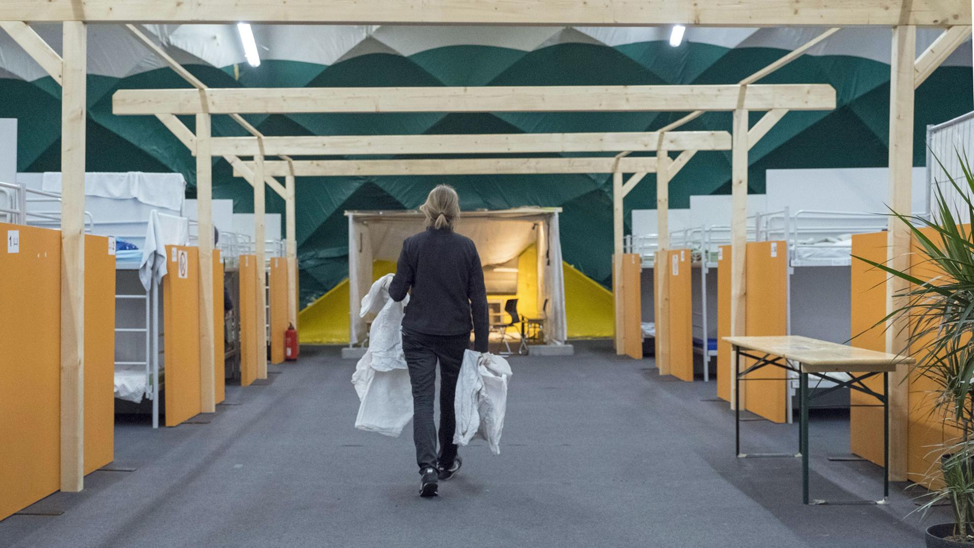 Obdachlosenunterkunft der Berliner Stadtmission in einer Traglufthalle am Güterbahnhof in Berlin-Lichtenberg (Foto vom 27.12.17: Die Leiterin Sabrina Bieligk bringt Bettwaesche). In Zusammenarbeit mit einem Hamburger Energiedienstleister hat die Berliner Stadtmission mit der Waermelufthalle Anfang 2014 ein Pilotprojekt gestartet, um neue Wege bei der Betreuung obdachloser Menschen in Berlin zu gehen. Die Halle wurde auf dem Gelaende des ehemaligen Gueterbahnhofs Wilmersdorf aufgestellt. Ueber etwa 1.000 Quadratmeter erstreckt sich die Lufthalle, die mit warmer Luft auf einer Temperatur zwischen 20 und 25 Grad beheizt wird. Seit November 2015 steht die HalleLuja , wie die Notunterkunft genannt wird, am Containerbahnhof in Berlin-Lichtenberg. Hier gibt es Schlafplaetze fuer 120 Maenner, Feldbetten, Kleidunng, Sanitaeranlagen und eine warm Copyright: epd-bild/RolfxZoellner Obdachlosenunterkunft der Berliner Stadtmission in einer Traglufthalle am Güterbahnhof in Berlin-Lichtenberg (Foto vom 27.12.17: Die Leiterin Sabrina Bieligk bringt Bettwaesche). In Zusammenarbeit mit einem Hamburger Energiedienstleister hat die Berliner Stadtmission mit der Waermelufthalle Anfang 2014 ein Pilotprojekt gestartet, um neue Wege bei der Betreuung obdachloser Menschen in Berlin zu gehen. Die Halle wurde auf dem Gelaende des ehemaligen Gueterbahnhofs Wilmersdorf aufgestellt. Ueber etwa 1.000 Quadratmeter erstreckt sich die Lufthalle, die mit warmer Luft auf einer Temperatur zwischen 20 und 25 Grad beheizt wird. Seit November 2015 steht die HalleLuja , wie die Notunterkunft genannt wird, am Containerbahnhof in Berlin-Lichtenberg. Hier gibt es Schlafplaetze fuer 120 Maenner, Feldbetten, Kleidunng, Sanitaeranlagen und eine warm Copyright: epd-bild/RolfxZoellner