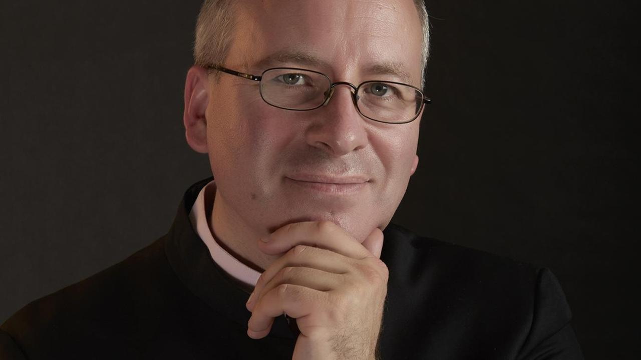 Ein Mann mit Brille schaut in die Kamera, wobei er eine Hand an sein Kinn gelegt hat. Ein Mann mit Brille schaut in die Kamera, wobei er eine Hand an sein Kinn gelegt hat.