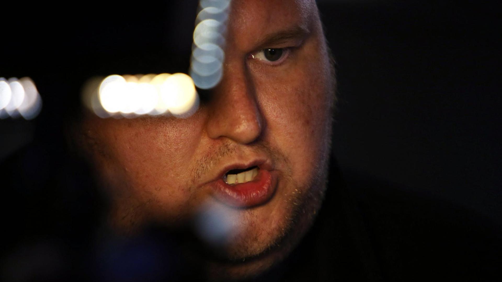 Porträt von Kim Dotcom, dessen rechtes Auge durch ein unscharfes Objekt im Vordergrund verdeckt wird. Porträt von Kim Dotcom, dessen rechtes Auge durch ein unscharfes Objekt im Vordergrund verdeckt wird.