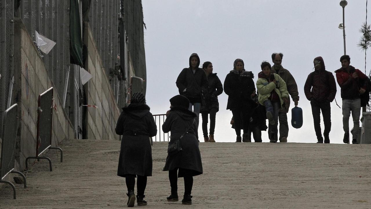 Flüchtlinge gehen im Registrierungszentrum auf der Insel Lesbos an einem Zaun entlang Flüchtlinge gehen im Registrierungszentrum auf der Insel Lesbos an einem Zaun entlang