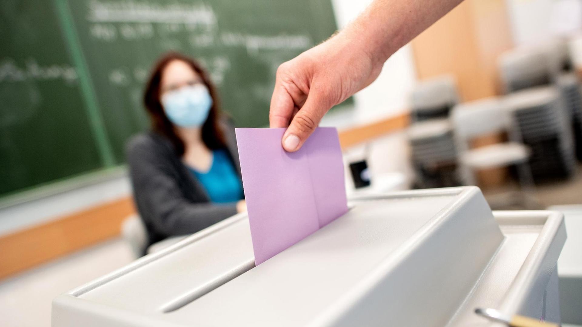 Ein Wähler wirft in einem Wahllokal, das im Klassenraum einer Schule untergebracht ist, seinen Stimmzettel in die Wahlurne. Ein Wähler wirft in einem Wahllokal, das im Klassenraum einer Schule untergebracht ist, seinen Stimmzettel in die Wahlurne.