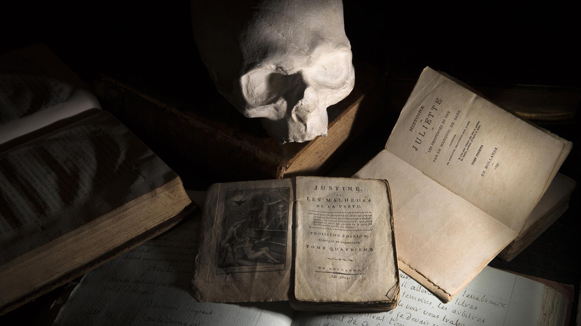 Ein Gipsabdruck des Totenschädels des Marquis de Sade ist neben älteren Ausgaben der Werke "Justine" (1801), "Juliette" (1797) und "L'union des arts ou les ruses de l'amour" (1810) zu sehen. Ein Gipsabdruck des Totenschädels des Marquis de Sade ist neben älteren Ausgaben der Werke "Justine" (1801), "Juliette" (1797) und "L'union des arts ou les ruses de l'amour" (1810) zu sehen.