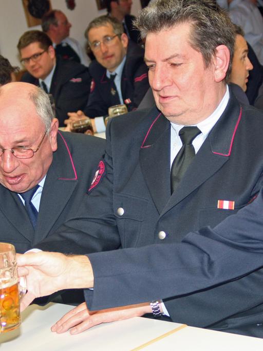 Altgediente Feuerwehrmänner bei der Jahreshauptversammlung der FFW Bad Wurzach prosten sich am 21.3.2013 zu.