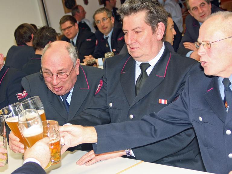 Altgediente Feuerwehrmänner bei der Jahreshauptversammlung der FFW Bad Wurzach prosten sich am 21.3.2013 zu.