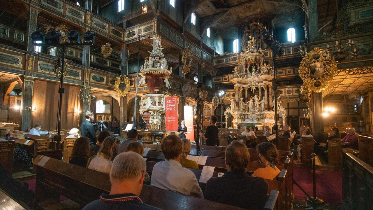 Publikum, das in einer reich geschmückten Kirche mit Abstand in den Bänken sitzt und zuhört. Publikum, das in einer reich geschmückten Kirche mit Abstand in den Bänken sitzt und zuhört.