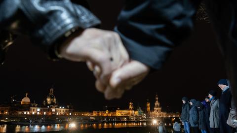 Teilnehmer der Menschenkette in Dresden halten sich an den Händen.