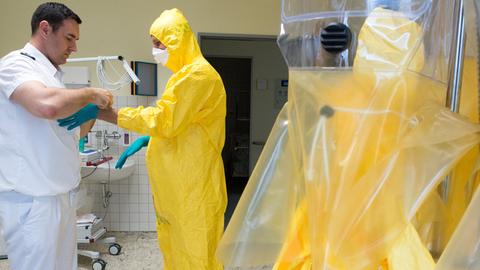 Im Bundeswehrkrankenhaus in Berlin stattet ein Soldat einen Freiwilligen mit einem Schutzanzug aus. Zweck: Eine Übung für Ebola-Helfer in Westafrika.