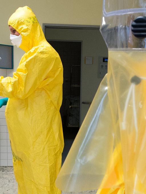 Im Bundeswehrkrankenhaus in Berlin stattet ein Soldat einen Freiwilligen mit einem Schutzanzug aus. Zweck: Eine Übung für Ebola-Helfer in Westafrika.