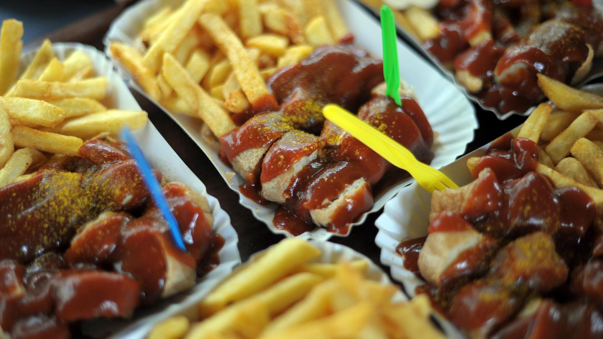 Pappteller mit Currywurst mit Pommes Frites steht auf einem Tisch in Konnopke's Imbiss in Berlin. Angeblich wurde die Currywurst 1949 in Berlin erfunden. Pappteller mit Currywurst mit Pommes Frites steht auf einem Tisch in Konnopke's Imbiss in Berlin. Angeblich wurde die Currywurst 1949 in Berlin erfunden.