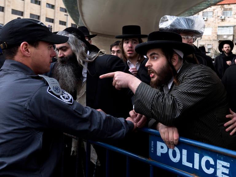 Hinter einer Absperrung beschimpfen ultraorthodoxe Juden in Jerusalem am 06.02.2014 die israelische Polizei.