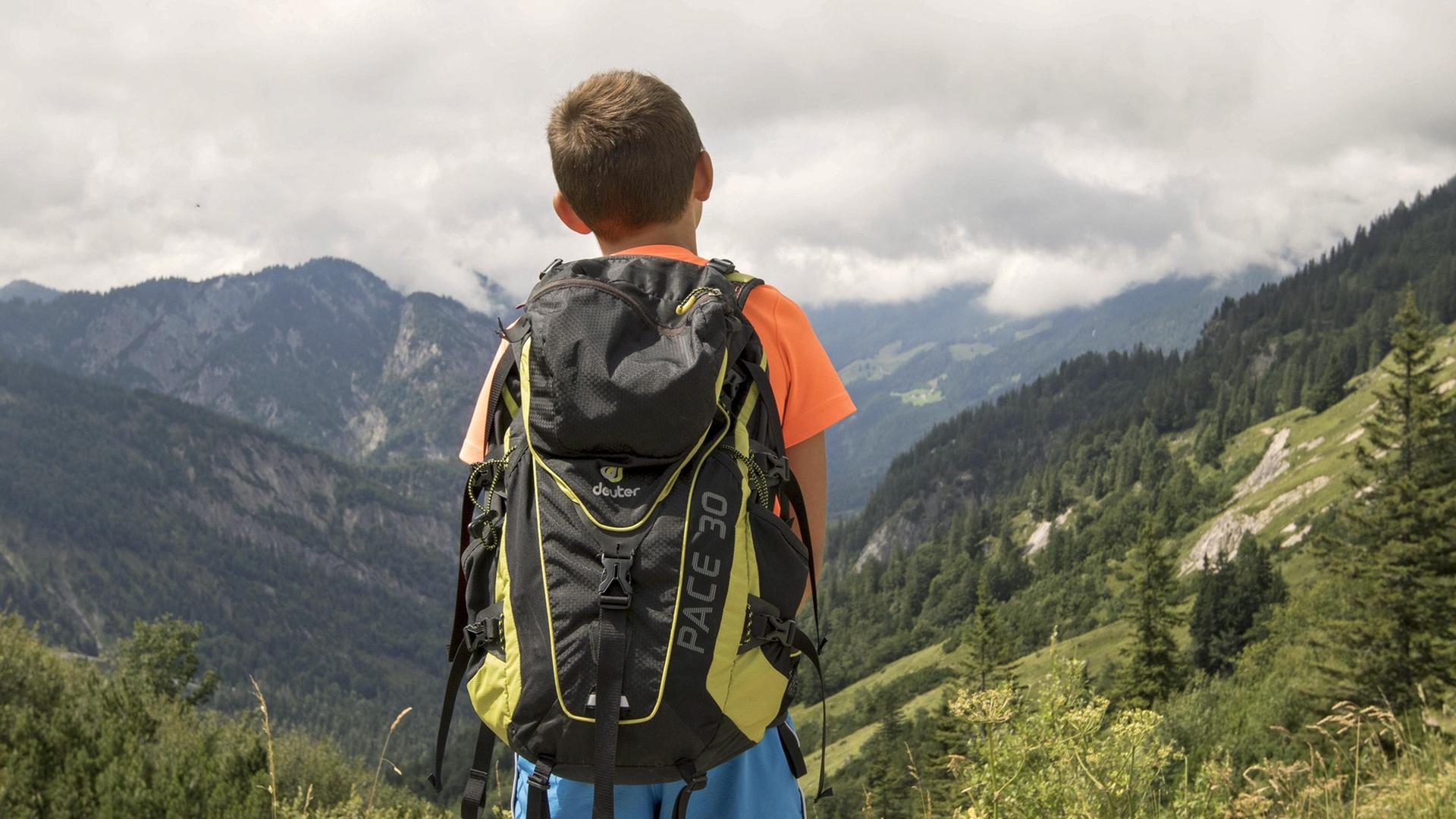 Ein junger Bergsteiger mit Rucksack blickt ins Kaisertal. Ein junger Bergsteiger mit Rucksack blickt ins Kaisertal.