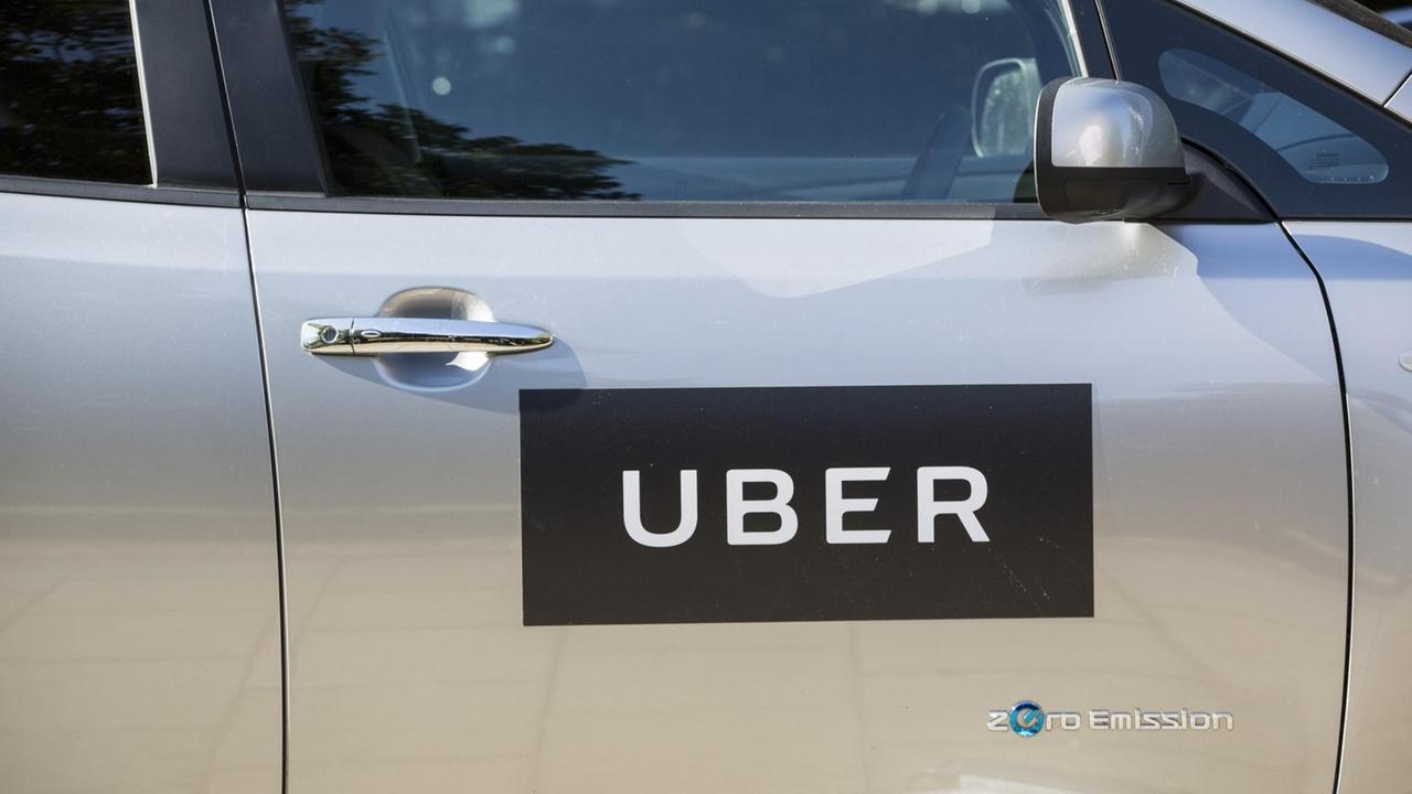 Das Logo des Fahrzeug-Vermittlungsdienstes Uber auf der Seitentüre eines grauen Pkw. Das Logo des Fahrzeug-Vermittlungsdienstes Uber auf der Seitentüre eines grauen Pkw.