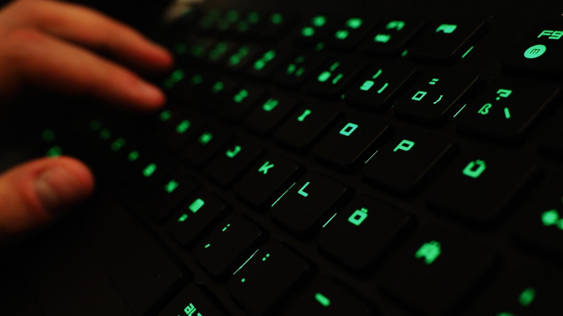 Ein Mann tippt auf einer beleuchteten Tastatur. Ein Mann tippt auf einer beleuchteten Tastatur.