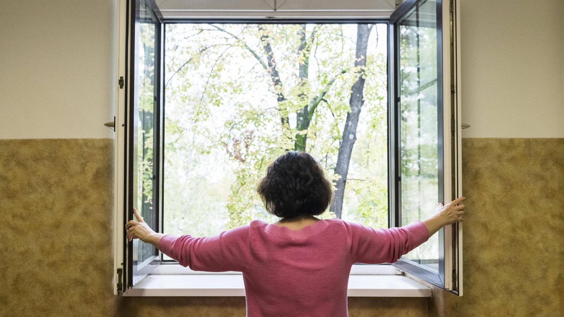 Eine Frau öffnet ein Fenster Eine Frau öffnet ein Fenster