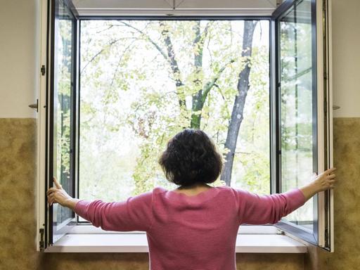 Eine Frau öffnet ein Fenster