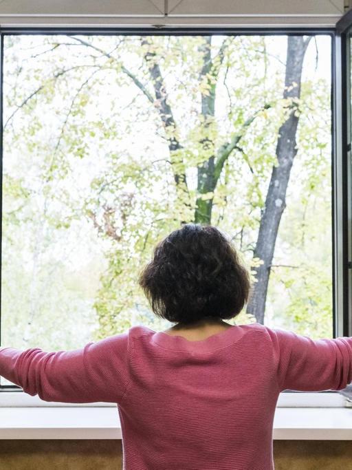 Eine Frau öffnet ein Fenster