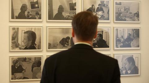 Ein Mann betrachtet Fotografien aus der Serie "Kirchfeldstraße, Düsseldorf" von Sigmar Polke in der Ausstellung vom Museum Morsbroich.