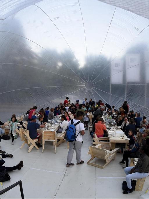 Menschen sitzen in dem Projekt "Kitchen Monument".
